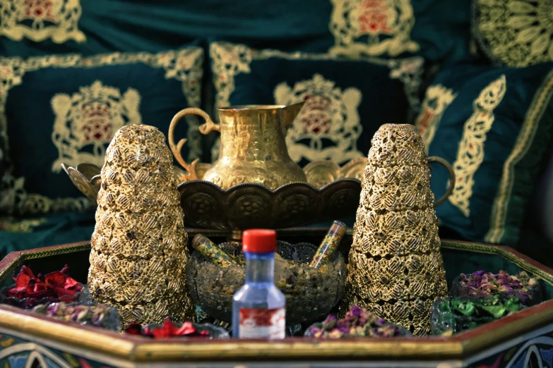 a gold teapot with pine cone shaped trees and other decor on a tray