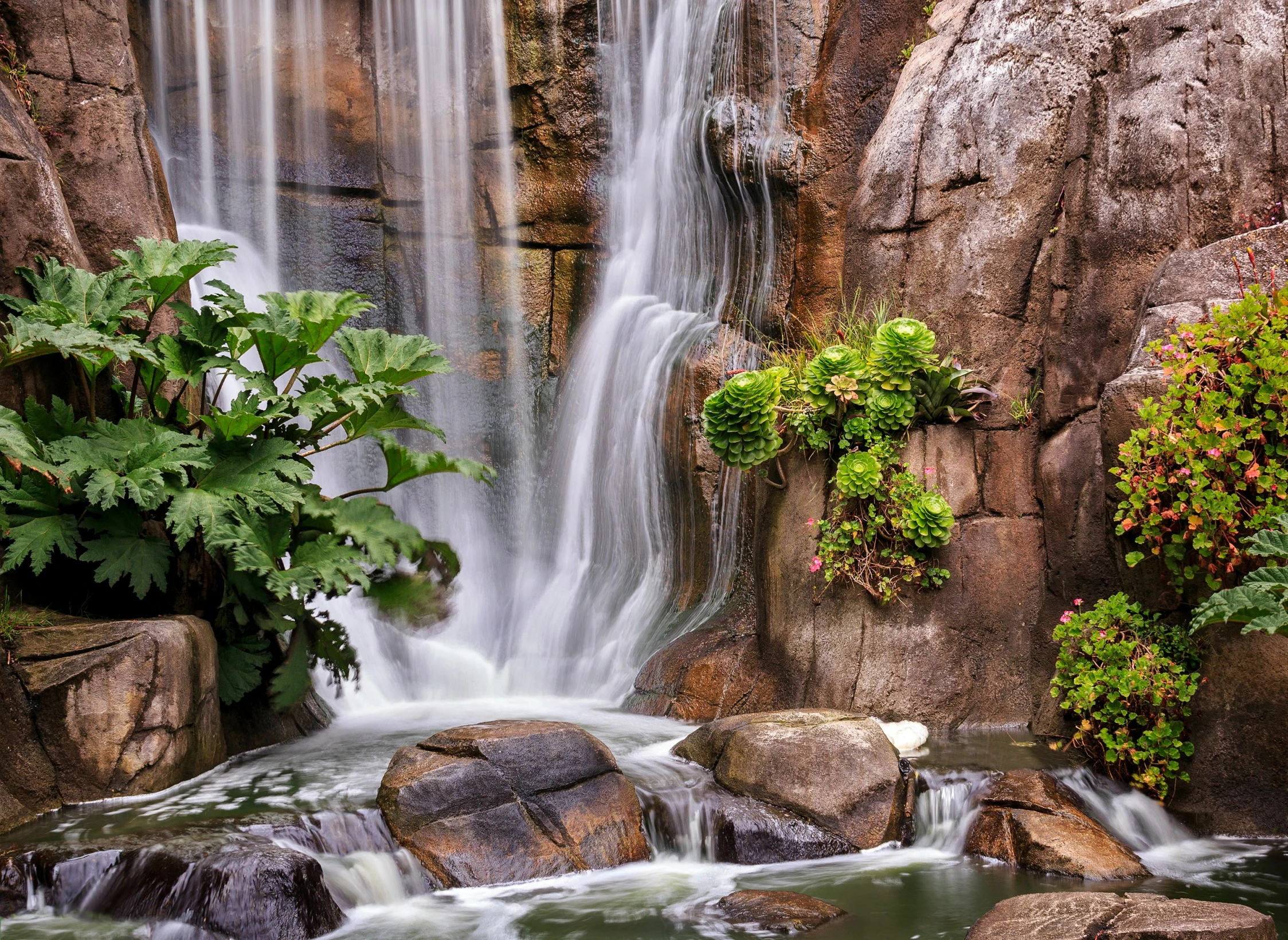 the waterfall is in the background of the rocks and trees