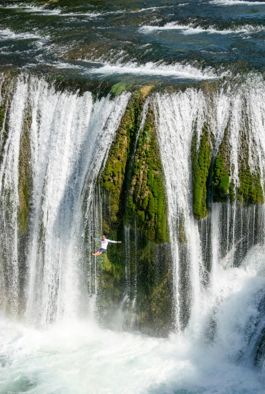 person on surfboard in mid air over a waterfall