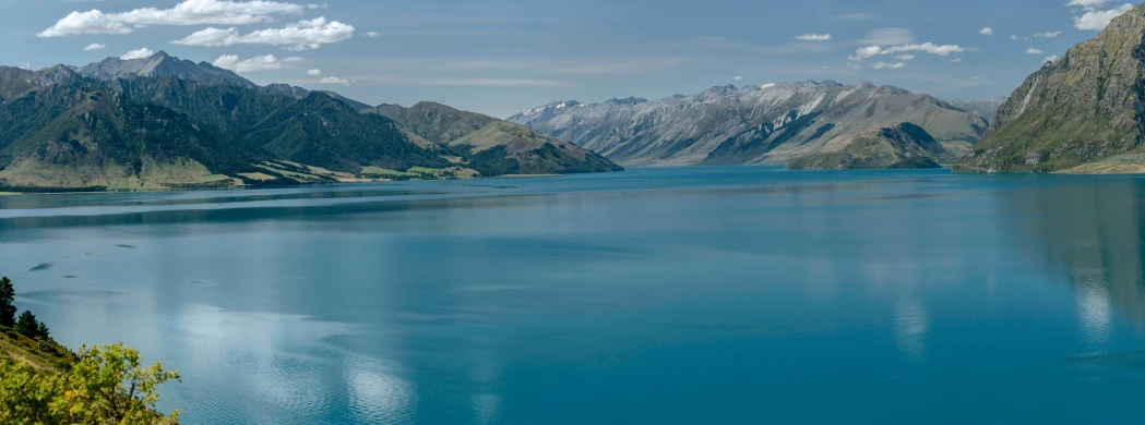 a blue lake surrounded by mountains and clouds