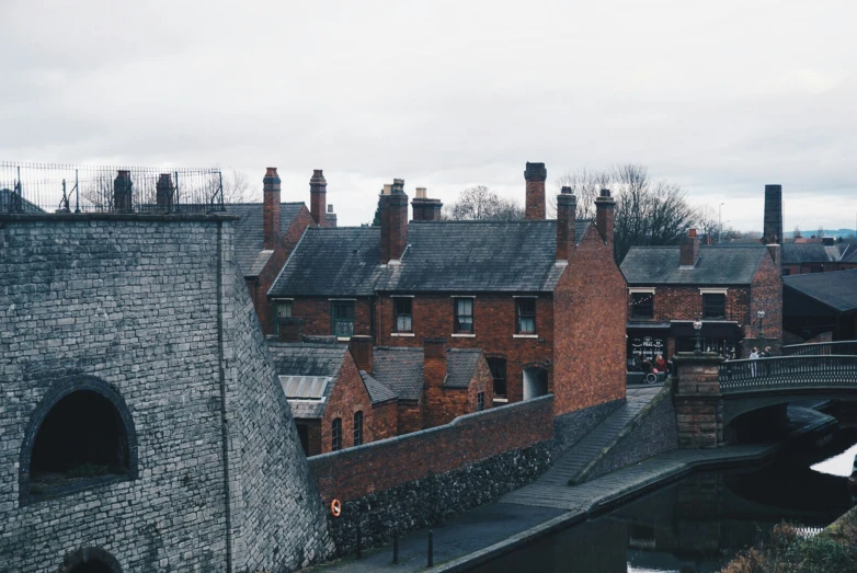 old brick buildings with arched windows and chimneys are shown along with a bridge