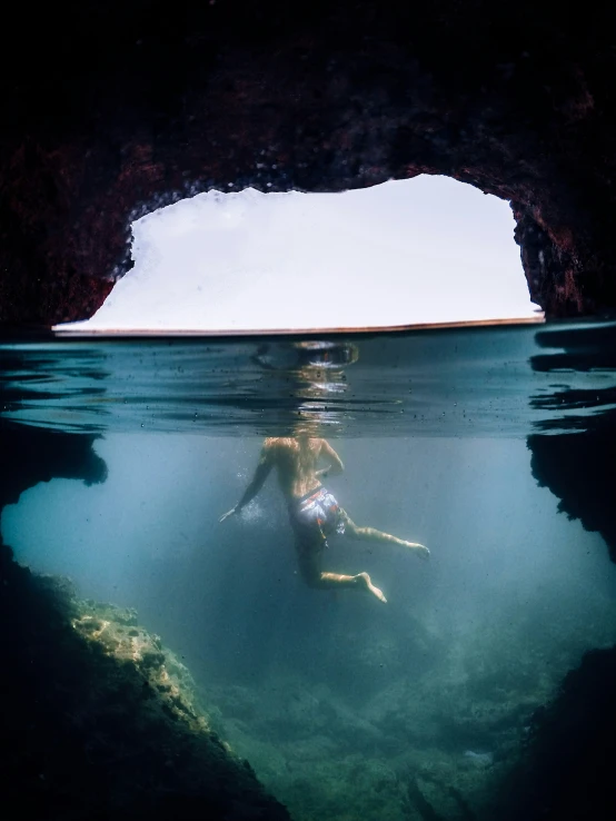 a man swims into a cave near an underwater tunnel