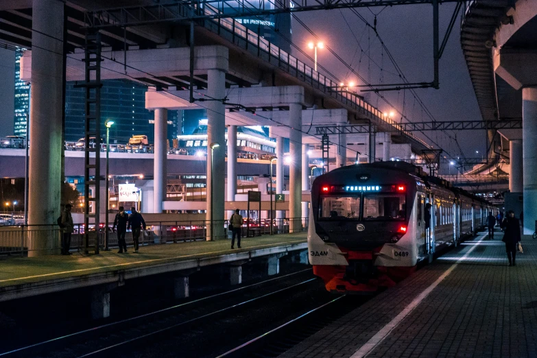 a train driving past some tall buildings at night