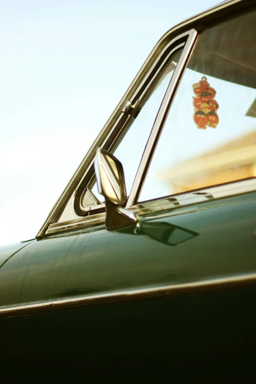 a side mirror of a green car with a sign in it