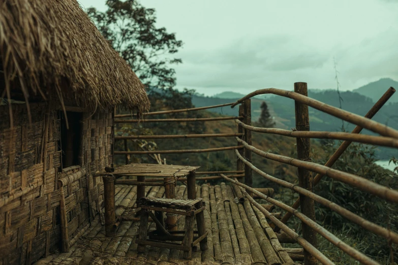 a rustic deck area with a straw roof, and table and chair