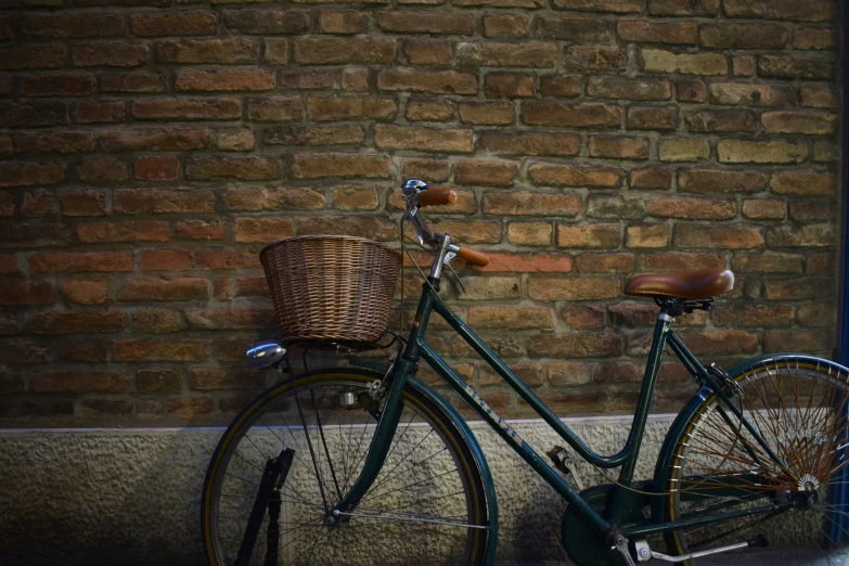 a bicycle with a basket is parked by a brick wall
