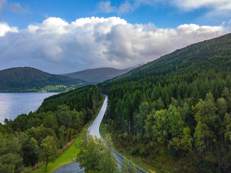 a winding, rural road sits at the bottom of a lush mountain