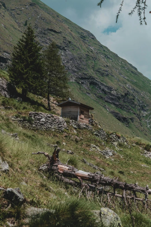 a house sits on the top of a hill near rocks and trees