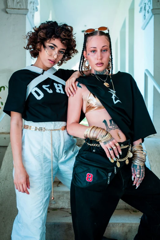 two women wearing matching shirts are standing on some steps