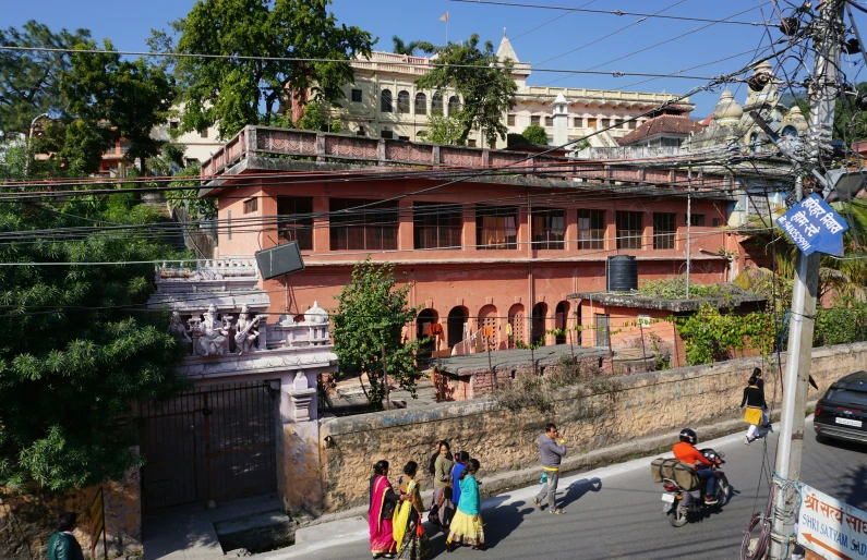 several people walk in the street in front of a very large building