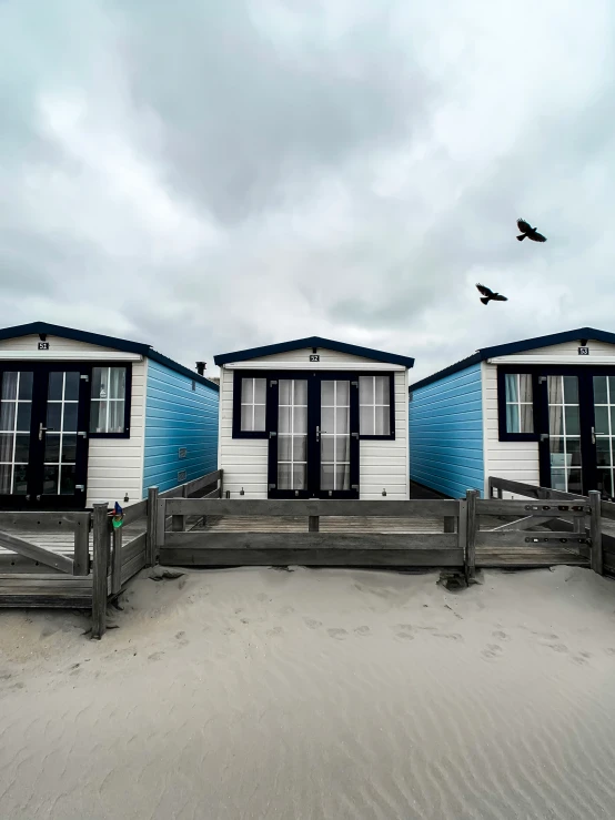 there is a small group of beach huts sitting on the sand