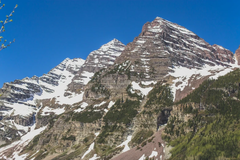 the mountains are covered in snow and have green trees on each side