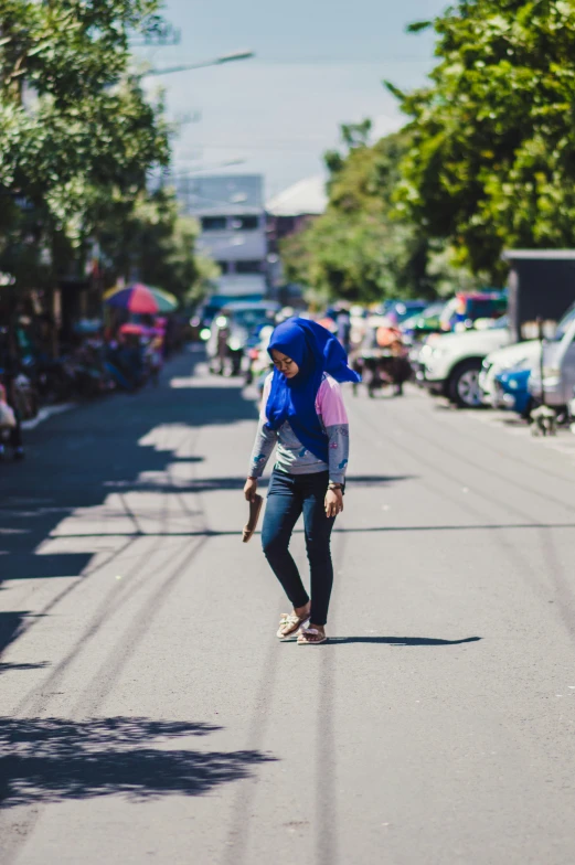 a woman walking down the street with a blue hat