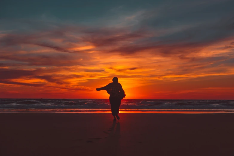 a person is standing on the beach at sunset