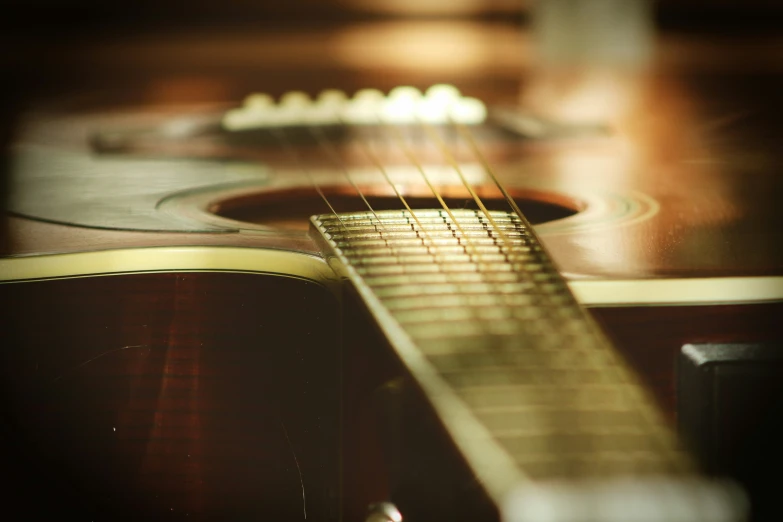 a brown acoustic guitar sitting on a wood table