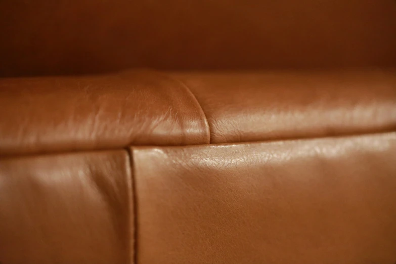 a tan leather chair and arm rest with no one on the back