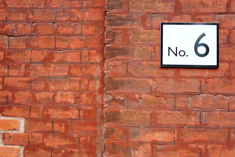 there is a white and black sign on a red brick wall