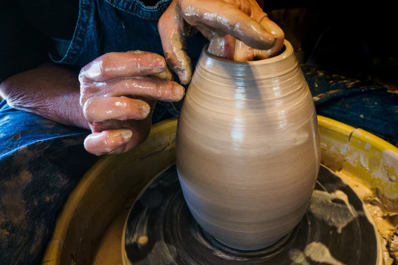 a person using a potters wheel to do pottery on a wheel