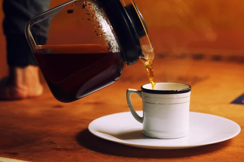 someone pouring coffee into a small cup sitting on the counter