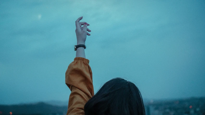 a person raising their arm with a sky in the background