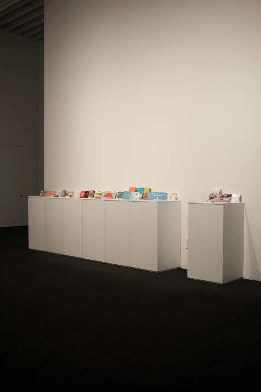 this room has a black floor, a white wall, and five shelves that hold cds and magazines