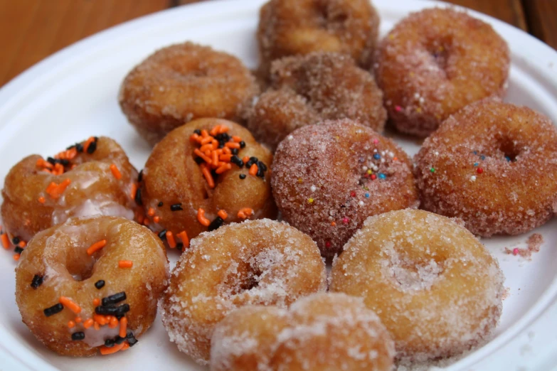 various donuts covered with sprinkles on a white plate