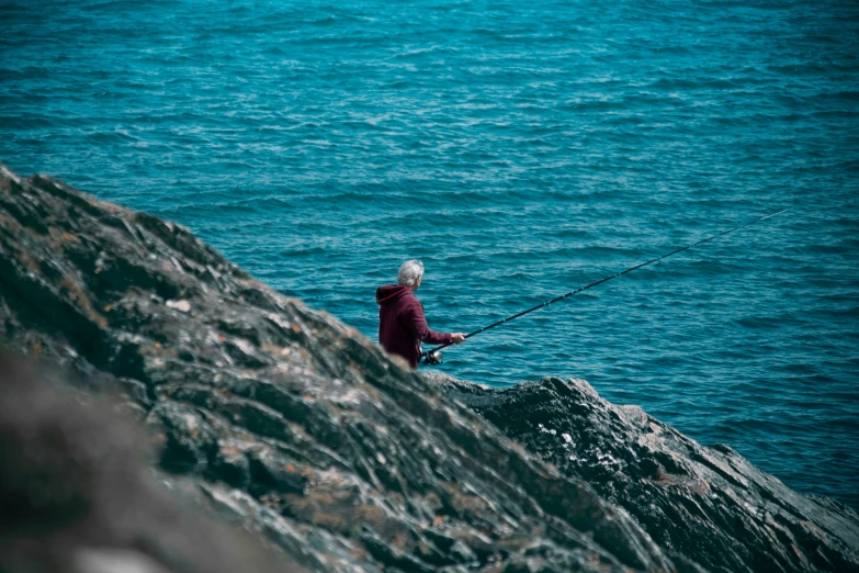 the man is fishing on the lake with a nice sail