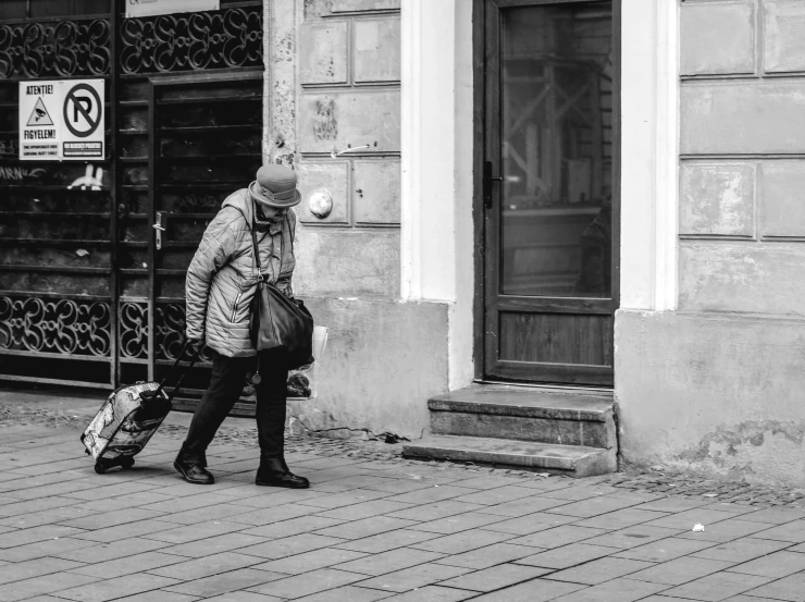 the woman is walking down the street holding her suitcase