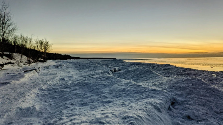 a snowboard rests on the sand near the water