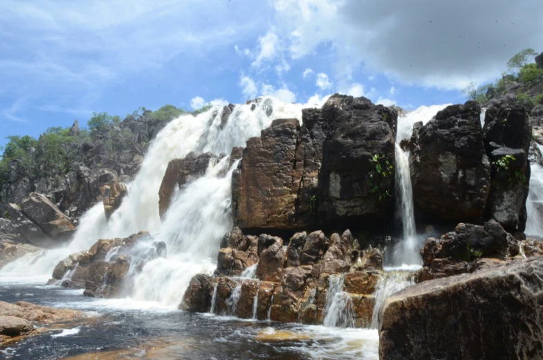 large waterfall with a small group of rocks on the bottom