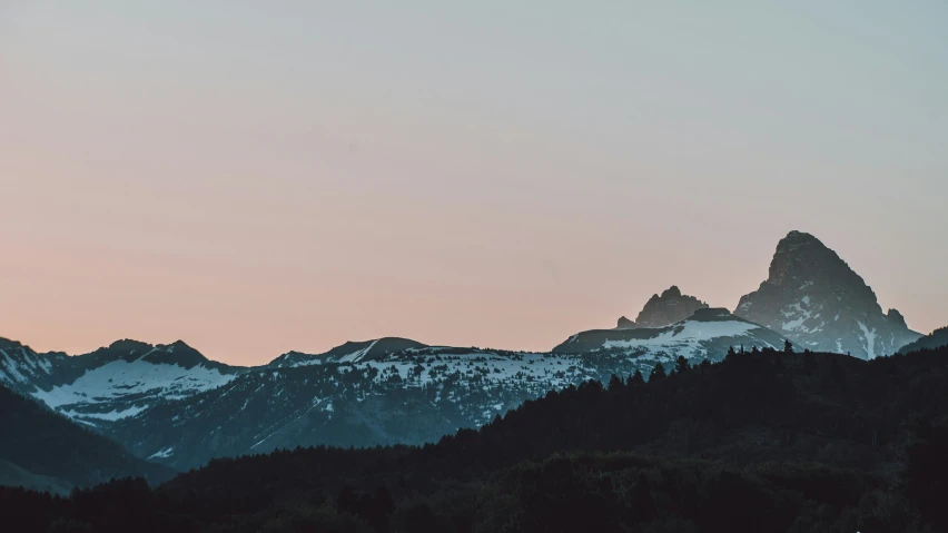 the snowy mountains at sunset are covered in snow