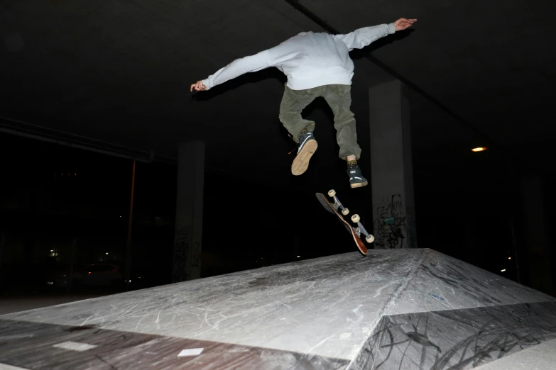 man in mid air over a ramp at night with skateboard