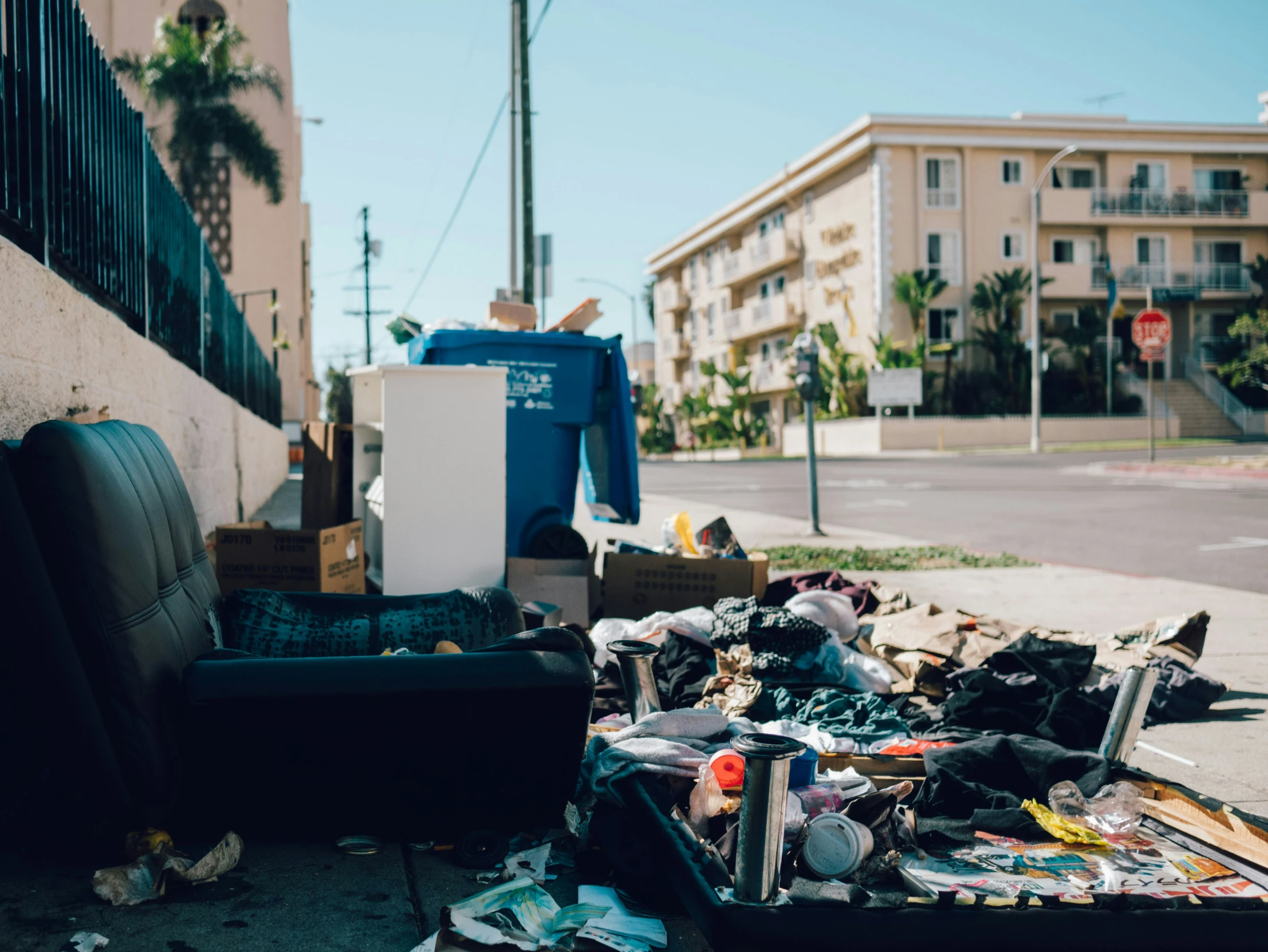 trash is laying on the sidewalk with buildings in the background