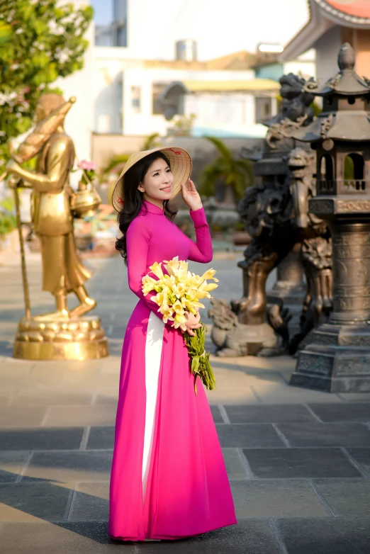 the woman in a pink long dress is holding flowers