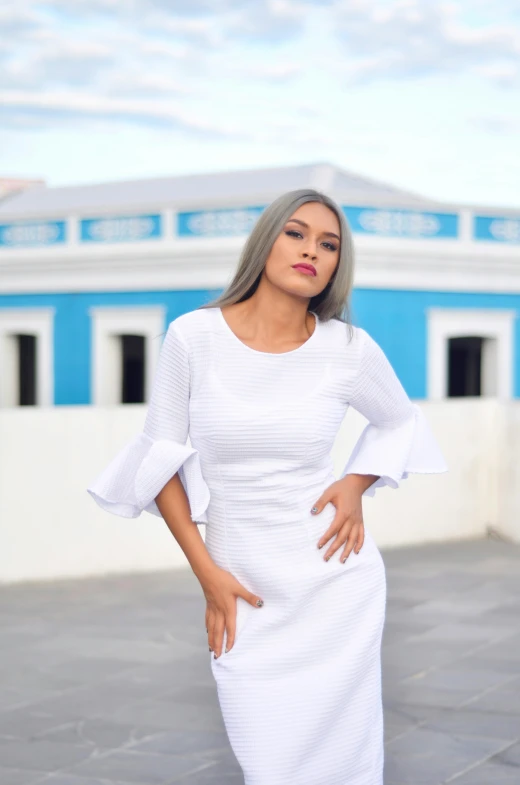 woman wearing white in front of a blue building