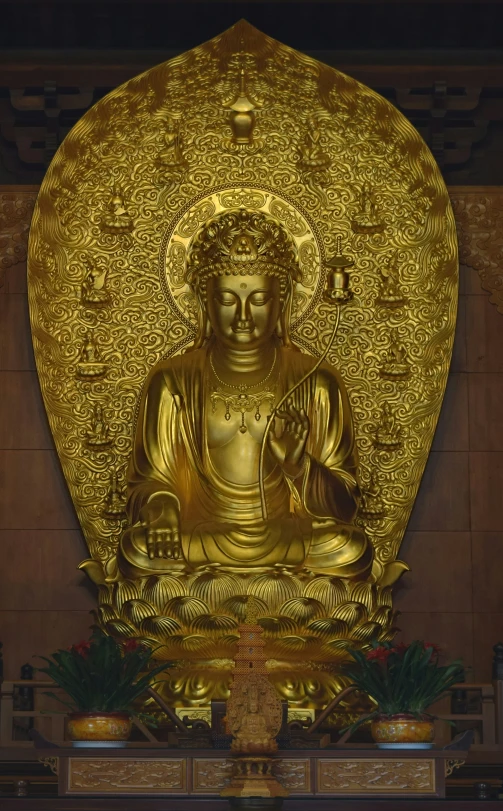 large golden statue surrounded by plants and candles