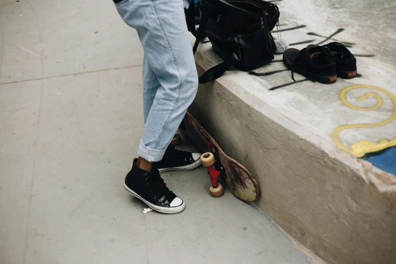 a skateboarder leaning against the cement ledge with his skate board