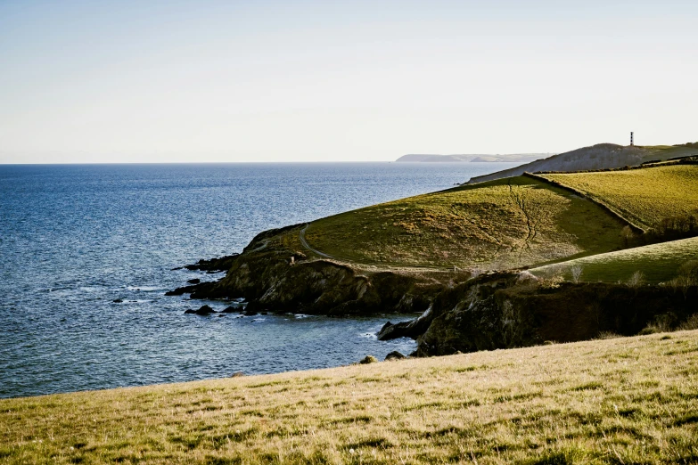 green grassy land with ocean and small hill near water