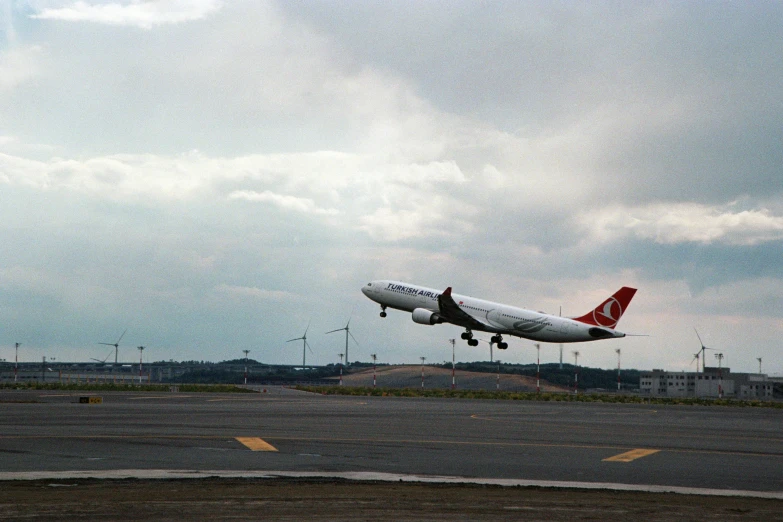 a jet plane flying over the ground in an airport