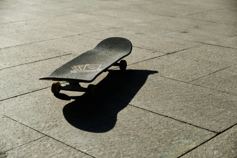 a skateboard casting a shadow on a paved ground