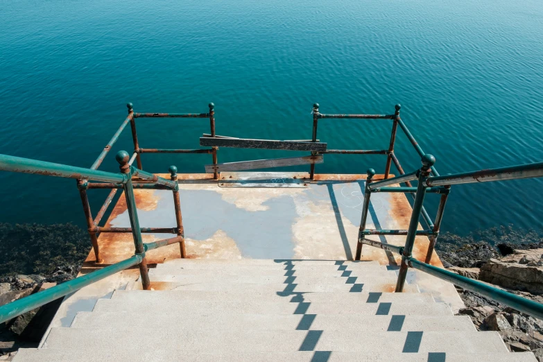 the stairs lead to the ocean from a metal structure