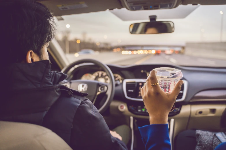 a person holding up a beverage in the car