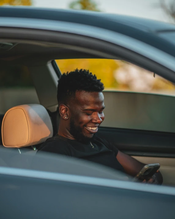 man sitting in his car and looking at his cell phone