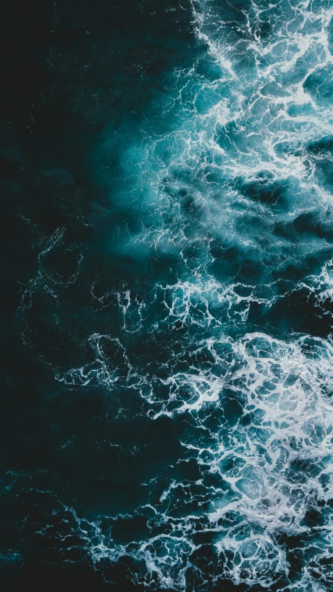 an aerial view of some blue waves crashing into each other