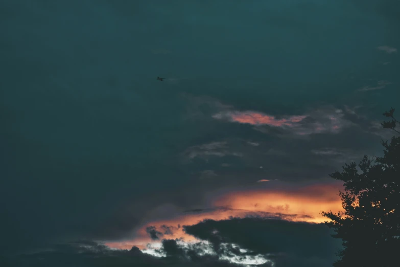 clouds and trees with setting sun in the distance