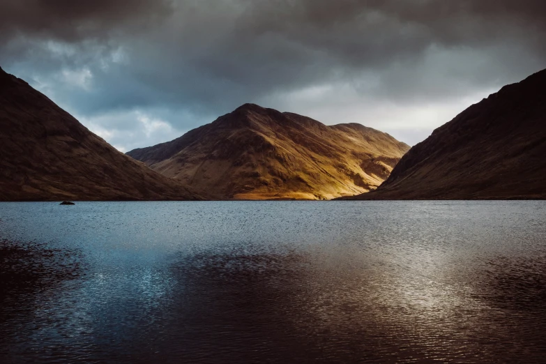 a boat is in the middle of a large lake with mountains behind it