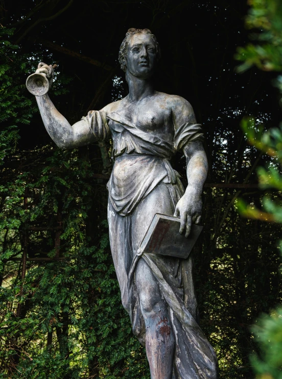 statue of woman holding book and a flower vase