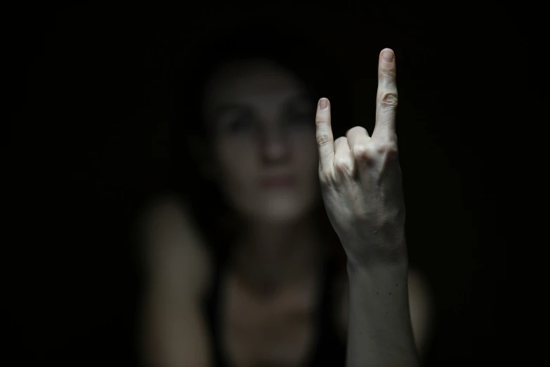 a woman holding up the peace sign in the dark