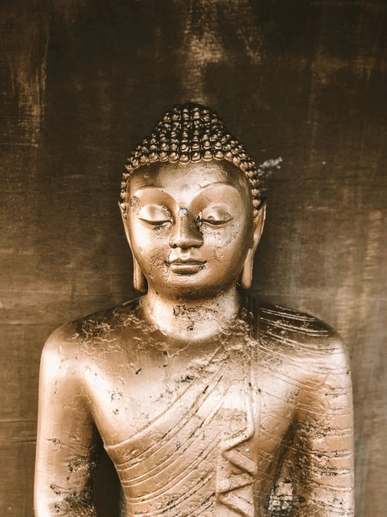 a gold statue of buddha sitting on a stool