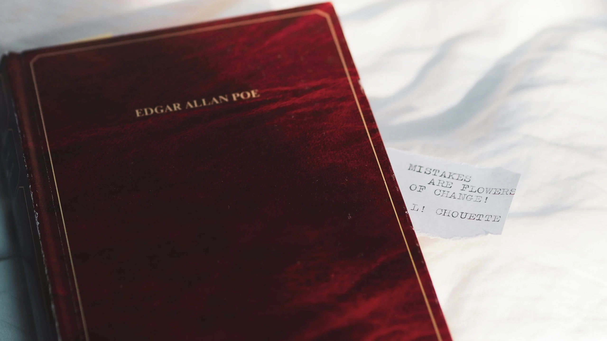 an elegant red book sits atop a plain white sheet